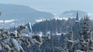 Blick vom Frognersettern zur kleinen Schanze (Glas-Stein-Bau links) Holmenkollen-Kirchturm rechts, TV-Kameras in Luftiger Höhe (Roter Liftarm) und Bygdøy-Halbinsel mit Yachthafen im Hintergrund